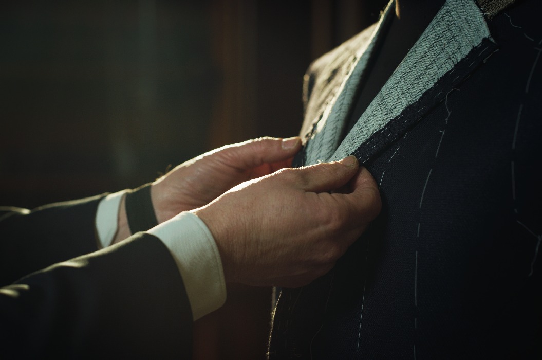 Filmische Aufnahme eines professionellen Schneiders, der Maß nimmt, um einen hochwertigen Maßanzug in einem luxuriösen Schneideratelier anzufertigen, Konzept von Mode, Handarbeit, Couturier und Geschäft